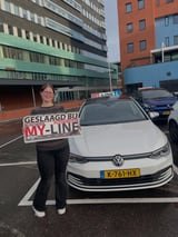 Geslaagde leerling met het bord van MY-Line bij de lesauto of lesmotor