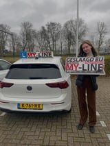 Geslaagde leerling met het bord van MY-Line bij de lesauto of lesmotor