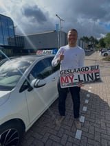 Geslaagde leerling met het bord van MY-Line bij de lesauto of lesmotor