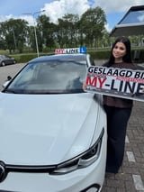 Geslaagde leerling met het bord van MY-Line bij de lesauto of lesmotor