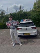 Geslaagde leerling met het bord van MY-Line bij de lesauto of lesmotor